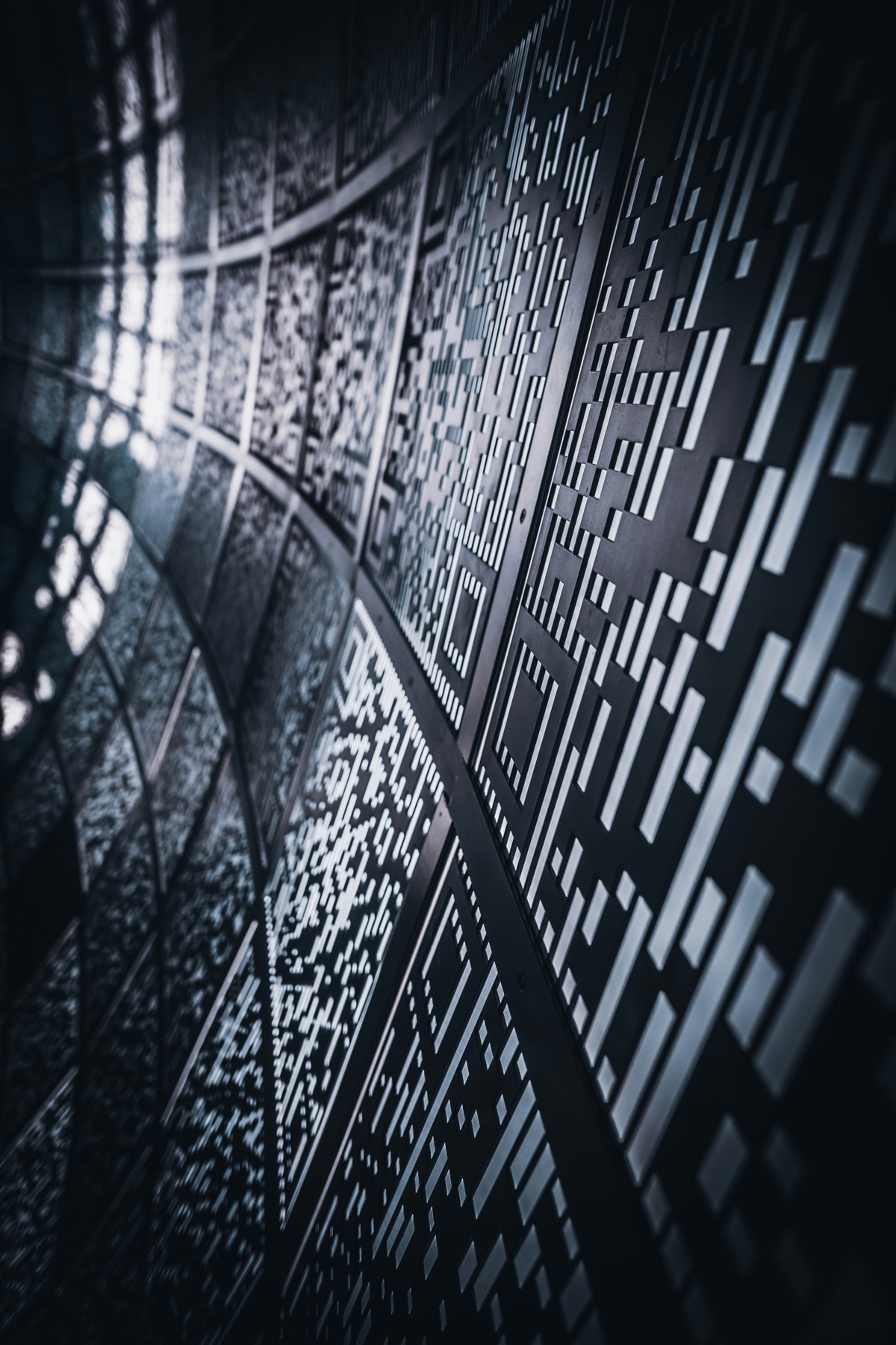 A close up of a perforated metal facade, its pattern receding into shadow
