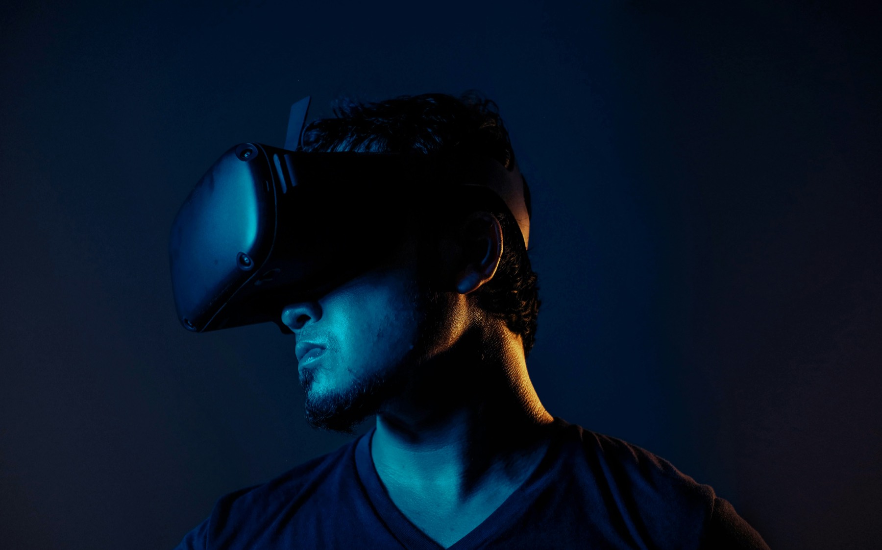 A person wearing an immersive headset, lit from one side in the dark